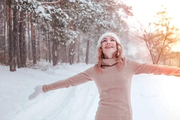 Christmas, holidays and season concept. Young happy woman blowing snow in the winter forest nature. Warm clothing knitted gloves and hat. — Stock Photo, Image