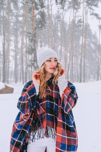 Dans eden kadın ormanda şapka ve panço giyerek geziyor, boho ve gezgin şehvet stili. Kış geliyor, ilk kar yağışı — Stok fotoğraf