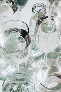 Güneş ışığında beyaz arka planda duran farklı güzel gözlükler gölgeler yaratır. Sert ışık, uzun gölgeler. Yaratıcı içki konsepti, alkol kokteyli. Cam kaplama konsepti. Geometrik şekiller