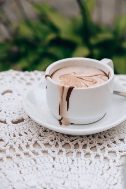 Yazın açık kafedeki masada sıcak çikolata kupası. Lokantada kahve ve kahvaltı zamanı. Çikolata, sıcak kaşlı süt, kakao. Sokak kafesi. Süt koyu çikolata.