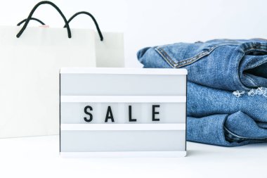 Kağıt alışveriş torbaları, kot giysileri olan kısa pano satışı. İnternetten alışveriş konsepti. Promosyon reklamcılığı. Tatil Siber Pazartesi.