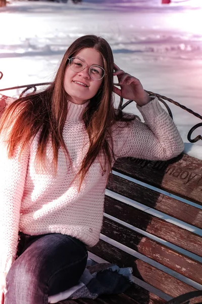在冬季公园里,戴着眼镜的漂亮年轻女子织了一件毛衣.室外寒冷的天气。雪姑娘笑容可亲的画像 — 图库照片