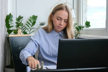 Genç bayan öğretmen masada oturuyor ve evde dizüstü bilgisayar kullanıyor. Eğitime geri dön. Öğrenci çevrimiçi ders alıyor. Mesafe öğrenme. Sınav hazırlığı. Yeni normal karantina