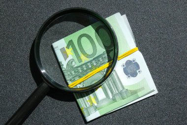 Avro destesinin arka planında büyüteç var. Yakın plan, yüz avroluk doku, arka plan. Zenginlik ve refah finansmanı iş bütçesi.