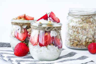 Sağlıklı kahvaltı. Yunan yoğurtlu yulaf ezmesi ve arka planda çilekli müsli. Vejetaryen, vejetaryen ve kilo verme diyeti. Detoks menüsü. Sağlıklı beslenme.