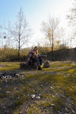 Gülümseyen beyaz ressamın portresi sonbahar parkında ahşap akustik gitar çalar. Genç söz yazarı, sonbahar zamanı dışarıda telli müzik aleti hobisi yapıyor. Sesli müzik doğal olarak iyileşir.