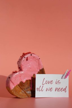 LOVE IS ALL WE NEED Valentines Day holiday greeting card idea Heart shaped strawberry berry croissant on pink background with copy space. Puff pastry new trendy sweet dessert bakery. Creamy dough