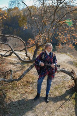 Sonbahar ormanlarında gitar çalan sarışın bir kadın var. Ses terapisi, akıl sağlığı ve sağlık ayinleri kavramı. Sakinlik sükuneti ses duyusal uygulamaları. Aura tarım enerjisi bütünsel