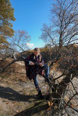 Gülümseyen beyaz kızın portresi sonbahar parkında ukulele çalıyor. Genç kadın, sonbahar zamanı dışarıda gitar enstrümanı çalıyor. Ses müziği doğal çevrede iyileşiyor. 
