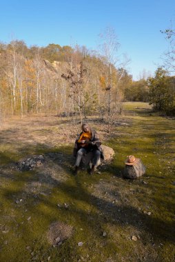 Sonbahar ormanında dışarıda gitar çalan sarışın bir kadın. Ses terapisi, akıl sağlığı ve sağlık ayinleri kavramı. Sakinlik sükuneti ses duyusal uygulamaları. Aura tarım enerjisi bütünsel
