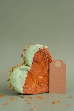 Boş kağıt nota şablonu oluşturur. Fotokopi alanı olan yeşil arka planda kalp şeklinde şam fıstıklı kruvasan. Puf puf yeni moda tatlı pastanesi. Kremalı hamur deneyi 