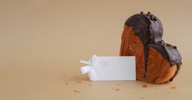 Boş kâğıt, tebrik kartı şablonu üzerine çikolata aromalı Ganache katılmış lezzetli kruvasan modeli. Eşsiz kalp şekilli fırın. Puf puf böreği bayram aşkı hediyesi hediye fikri