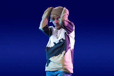 Stüdyoda günlük kıyafetlerle dans eden Latin kadın ve mor arka plan.