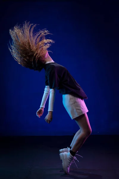 Latin kadın dans ediyor stüdyoda poz veriyor, saçları hareket halinde.