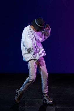 Stüdyoda dans eden Latin çocuk. Mavi ve mor arka planlı.