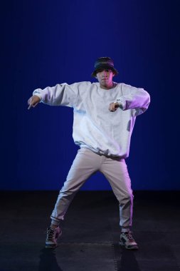 Stüdyoda dans eden Latin çocuk. Mavi ve mor arka planlı.