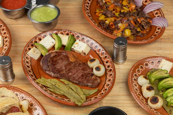 Mexicaans eten, gesneden vlees geserveerd op een bord met nopal, avocado en ui op een houten tafel — Stockfoto