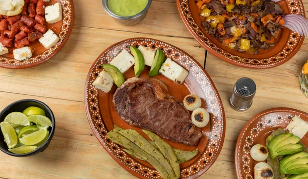 Mexicaans eten, gesneden vlees geserveerd op een bord met nopal, avocado en ui op een houten tafel — Stockfoto