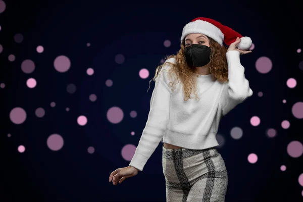 Lateinische Frau in Weihnachtskleidung mit Maske, die auf einen Raum für Werbetexte zeigt — Stockfoto