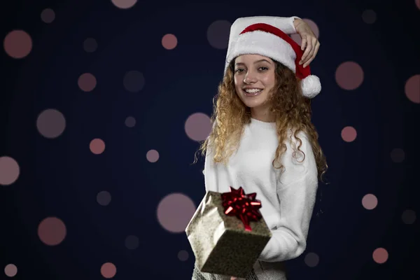 Junge lateinische Frau, die ein Weihnachtsgeschenk mit Weihnachtsmann-Hut zeigt. Raum für Text — Stockfoto