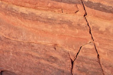 Kızıl kayanın desenli yüzeyi doğal desenler ve jeolojik özellikler sergiliyor, doğanın sanatının ve yeryüzünün tarihinin güzelliğini gözler önüne seriyor.