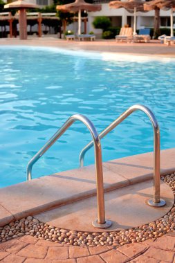 Yüzme havuzunda berrak sulara açılan paslanmaz çelik bir merdiven var. Etrafı çakıllı kenarlar ve sakin bir atmosfer için güneş panelleri ile çevrili.