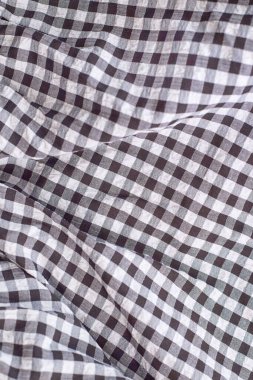 Siyah ve beyaz kareli kumaş yumuşak kıvrımlı bir kumaş sergiliyor, görsel olarak çekici bir desen ve derinlik yaratıyor.