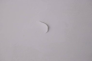 Hasarlı bir duvarın yakın görüntüsü boyayı gösteriyor, alttaki yüzey dokusunu ortaya çıkarıyor, ilginç bir görsel detay yaratıyor.