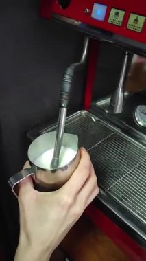 Bir el, paslanmaz çelik sürahide süt köpürtmek için buhar çubuğu kullanıyor. Kahve içecekler için kremalı doku yaratıyor.