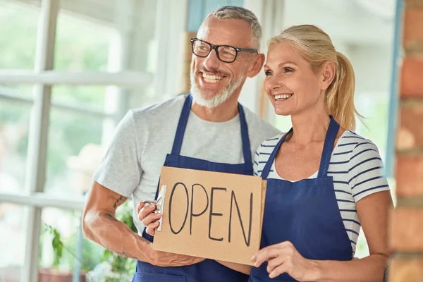 Middle aged caucasian owners of shop with open board