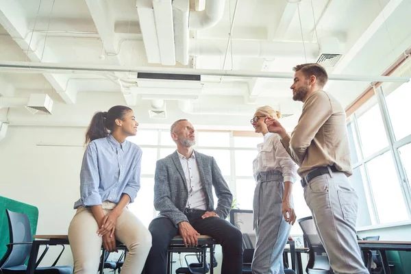 Grupo de equipo de negocios multirraciales discutiendo algo y comunicándose mientras trabajan juntos en el moderno espacio de coworking, teniendo una reunión — Foto de Stock