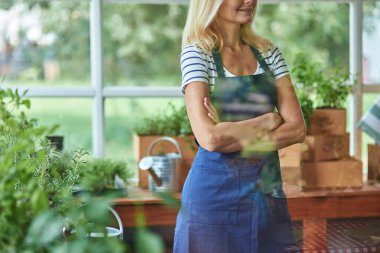 Önlüklü kadın elleri çapraz duruyor.