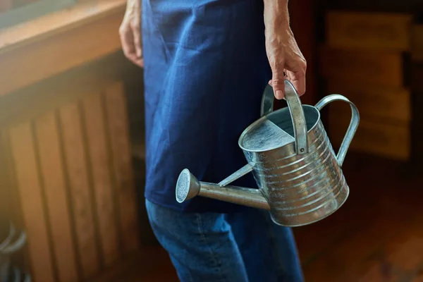 Selective focus on watering can in working woman hand