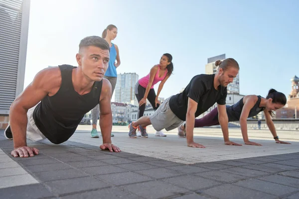 Unga blandade race idrottare gör armhävningar på torget — Stockfoto