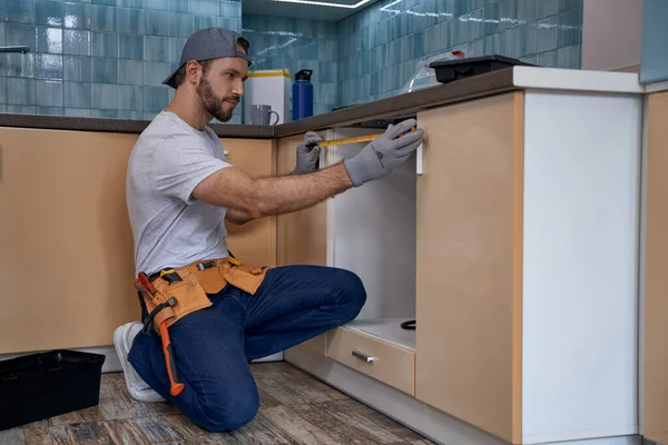 Young caucasian builder with measuring tape near kitchen drawer — Stock Photo, Image