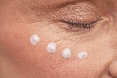 Gözü kapalı ve yüzünde serum olan olgun bir kadın.