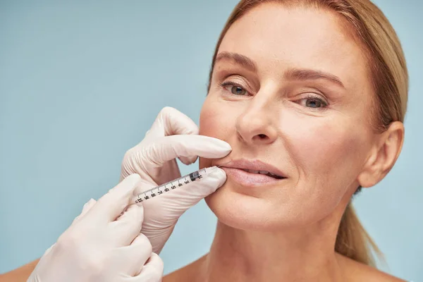 Hermosa mujer caucásica madura haciendo procedimiento de aumento de labios por cosmetólogo — Foto de Stock