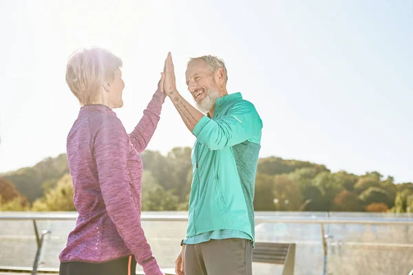 Partnerschaft. Glückliches Familienpaar, reifer Mann und Frau in Sportkleidung geben High Five nach dem Training im Stadtpark an einem sonnigen Morgen — Stockfoto