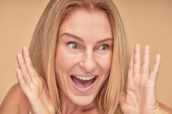 Gros plan portrait de femme mature excitée avec regard surpris sur fond beige — Photo