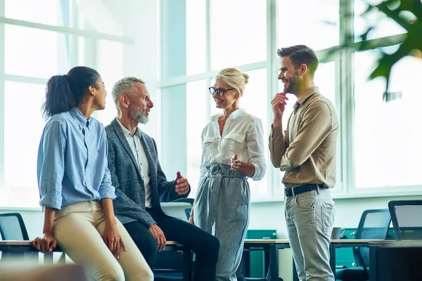 Groep van succesvolle multiraciale mensen communiceren en bespreken van zaken terwijl ze in het moderne kantoor staan na een ontmoeting — Stockfoto