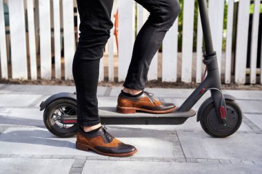 Oraya git. Havalı, olgun bir iş adamının elektrikli scooterıyla dışarıda dikilirken yakın plan çekimi.