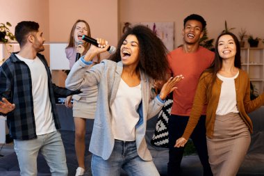 Şarkı söylemek mutluluk demektir. Mikrofon tutan ve karaoke partisinde en iyi arkadaşlarıyla şarkı söyleyen oldukça karışık ırk kızı. Mutlu çok kültürlü insanlar birlikte vakit geçiriyor.