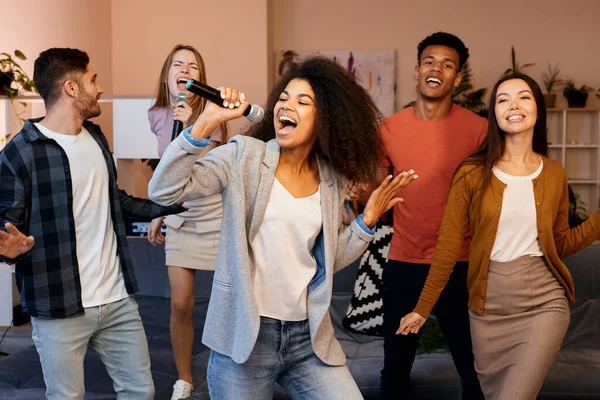 Şarkı söylemek mutluluk demektir. Mikrofon tutan ve karaoke partisinde en iyi arkadaşlarıyla şarkı söyleyen oldukça karışık ırk kızı. Mutlu çok kültürlü insanlar birlikte vakit geçiriyor.