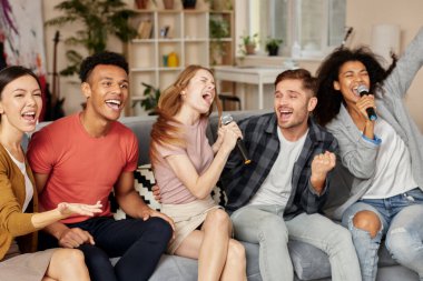 Anlar müzikle dolu. Evde karaoke yapan, oturma odasındaki kanepede otururken mikrofonla şarkı söyleyen heyecanlı, çok kültürlü genç arkadaşlar.