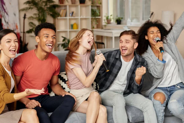 Anlar müzikle dolu. Evde karaoke yapan, oturma odasındaki kanepede otururken mikrofonla şarkı söyleyen heyecanlı, çok kültürlü genç arkadaşlar.