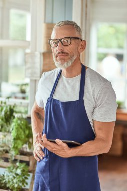 Tablet tutan orta yaşlı beyaz bir adam.