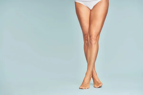 Idealna depilacja. Przycięte zdjęcie kobiety z idealnie ogolonymi nogami stojącej nad niebieskim tłem — Zdjęcie stockowe