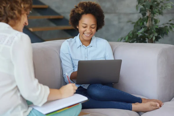 Gadis remaja yang lucu tersenyum, menggunakan laptop untuk belajar sambil belajar dengan guru perempuannya, duduk di sofa di rumah — Stok Foto