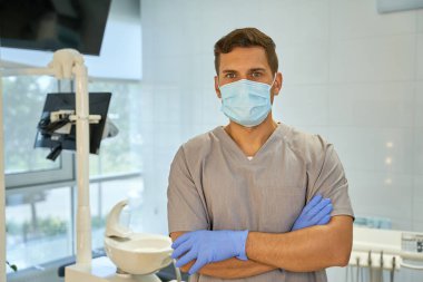 İş yerinde maske ve eldiven takan erkek diş teknisyeni.