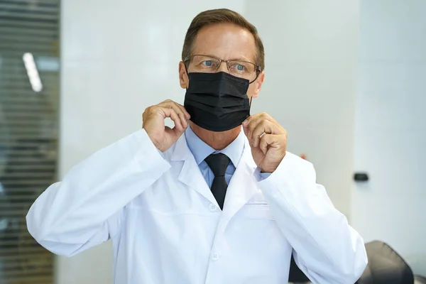 Medveten läkare som täcker ansiktet med skyddsmask — Stockfoto